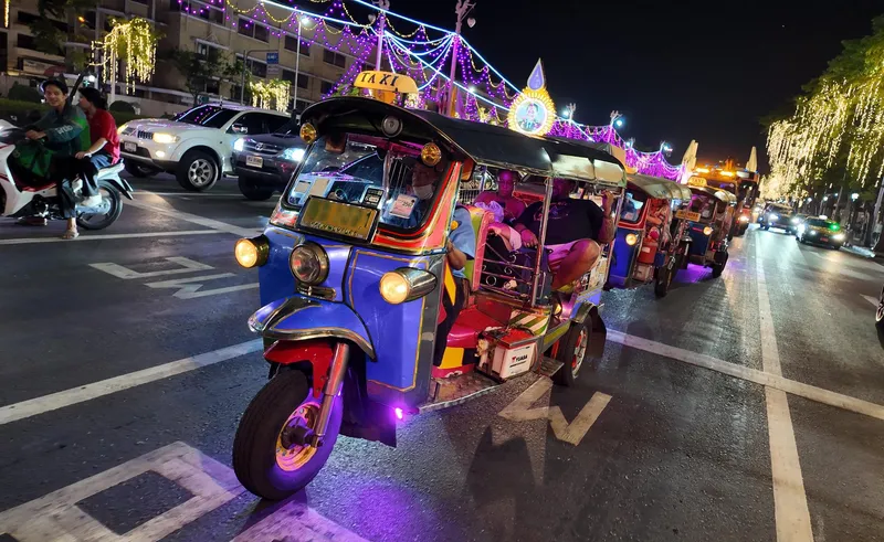 Private tuk tuk driving through Bangkok's neon-lit nightlife streets at night on an exclusive private tuk tuk tour Bangkok for couples